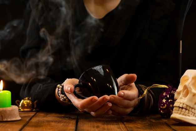 Fortune teller or oracle with holding a black cup for fortune telling on the coffee grounds