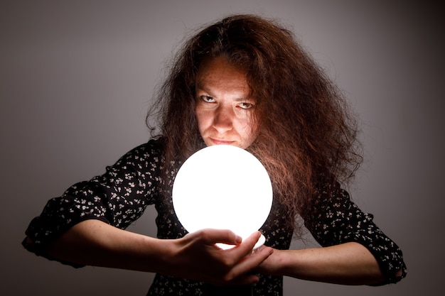 Fortuneteller holding a glowing ball in her hands.