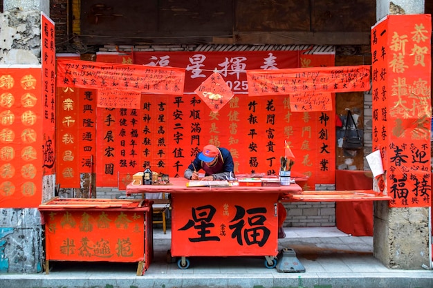 Foshan Guangdong provincie China 14 JANUARI 2022 Mensen schrijven coupletten met groeten voor Lentefestival Voorbereiding voor Chinese nieuwjaarsviering in Kuaizi-straat in Foshan