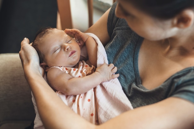 Foto bovenaanzicht van een blanke moeder met sproeten die haar pasgeboren baby vasthoudt, bedekt met een quilt