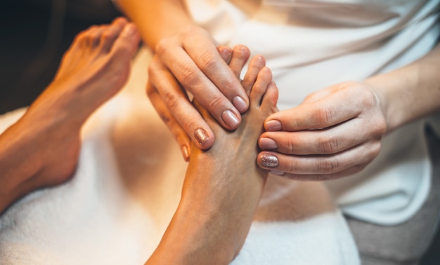 Foto bovenaanzicht van een kuuroordmedewerker die een voetmassagesessie heeft bij de kuuroordsalon met een jonge cliënt