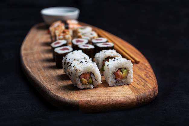 Foto de stock de composiciÃ³n de sushi con Maki, California Roll y Nigiri con palillos y salsa de soja sobre tabla de madera.