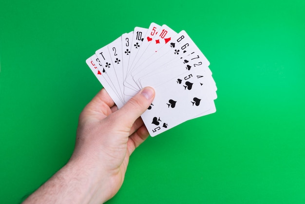 Foto die van een mandhand, speelkaarten op groen houdt