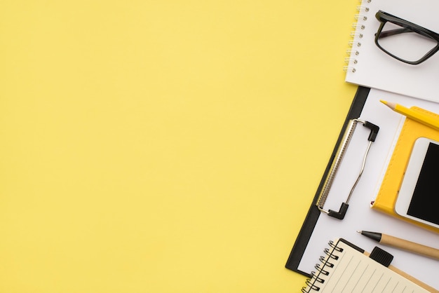 Foto hierboven van notebook pen potlood bril en telefoon geïsoleerd op de gele achtergrond