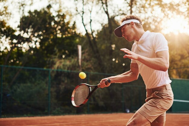 Foto in beweging. jonge tennisser in sportieve kleding is buiten op het veld.