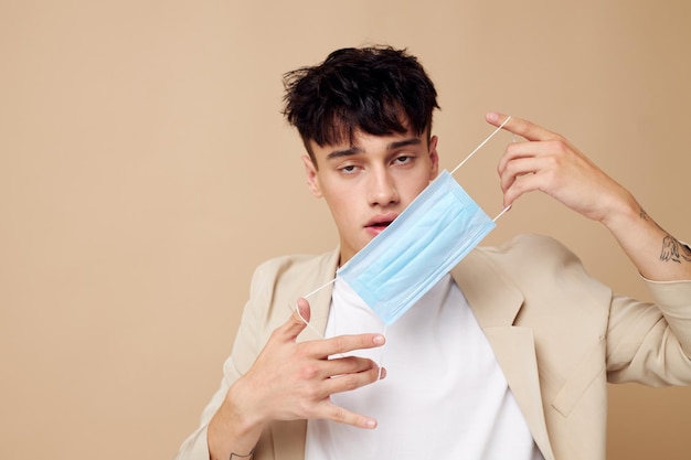 Foto jonge vriend met een medisch masker in de handen van poserende mode lichte achtergrond ongewijzigd