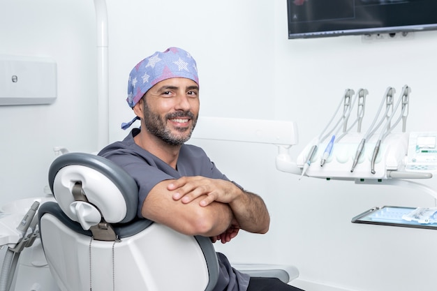 Foto met kopieerruimte van een mannelijke tandarts die op een stoel zit in een kliniekkamer met medische apparatuur