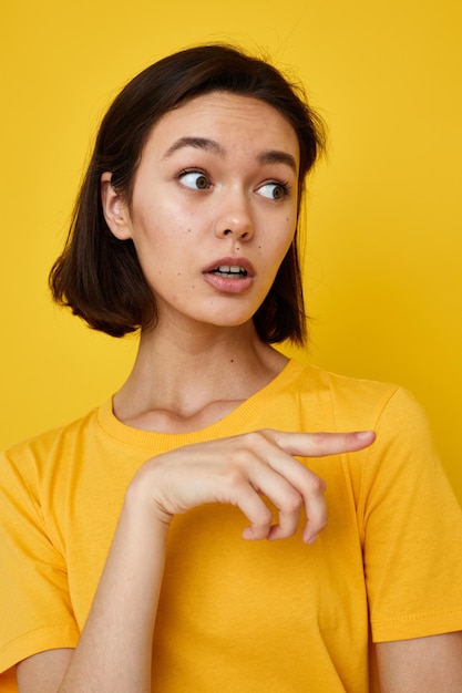 Foto mooi meisje gele t-shirt zomer stijl handgebaar geïsoleerde achtergrond