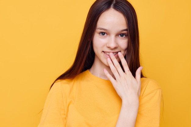 Foto mooi meisje in een gele t-shirt emoties zomer stijl gele achtergrond