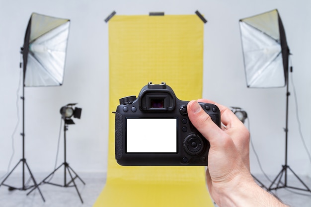 Foto nemen met camera in een fotostudio met gele achtergrond en licht apparatuur