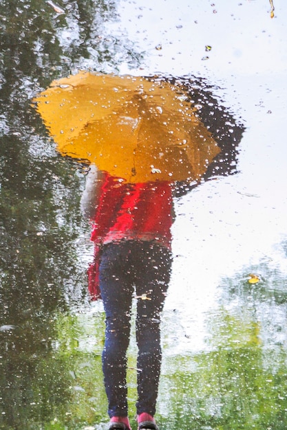 Foto foto op water van een regen, meisje met een gele paraplu