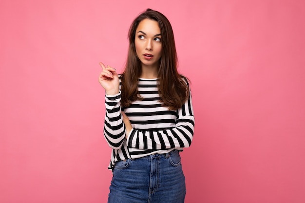 Foto-opname van een schattige, aantrekkelijke, vrij bedachtzame dromende jonge brunette vrouw die een casual gestreept draagt