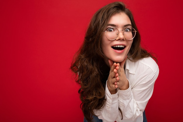 Foto-opname van mooie verbaasde positieve jonge brunette vrouw die vrijetijdskleding draagt en stijlvol is