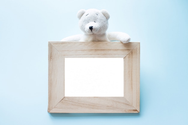 Foto oud houten kader met enige witte teddybeerzitting op blauw.