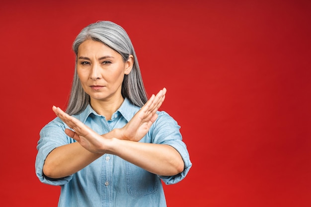 Foto portret oudere senior volwassen vrouw weergegeven: stop of geen teken met hand geïsoleerd op rode achtergrond