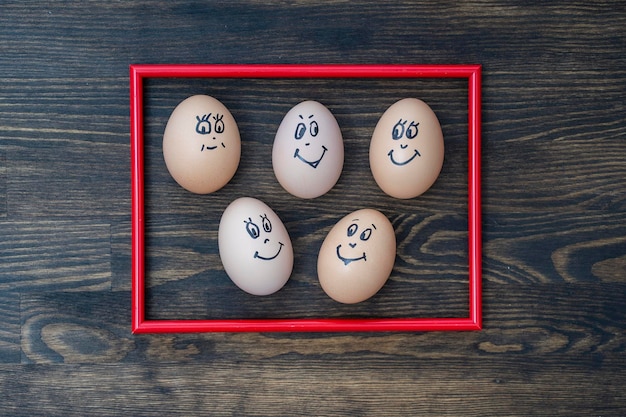 Foto rood frame en veel grappige eieren glimlachend op houten muur achtergrond close-up Eieren familie emotie gezicht portret Concept grappig voedsel