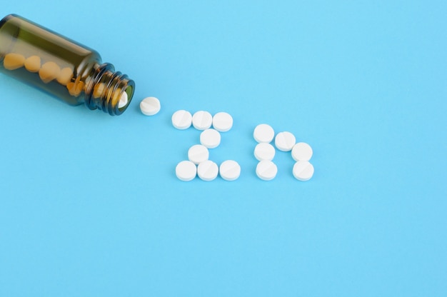 Foto's creatief concept voor medische fles met witte pillen op blauwe achtergrond, vitamine zink, letters bekleed met pillen