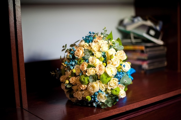 Foto's van het bruidsboeket in blauwe en witte kleuren die op de plank liggen bruidsboeket van rozen en blauwe bloemen