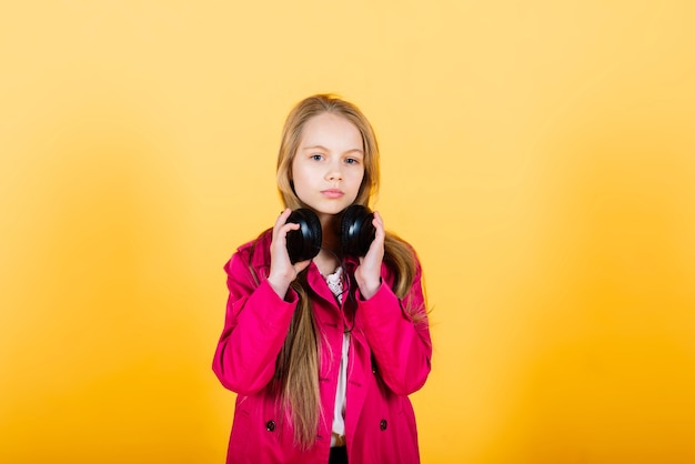Foto van aantrekkelijk meisje met behulp van draadloze hoofdtelefoons geïsoleerd op gele achtergrond, studio