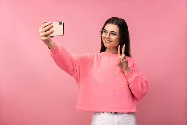 Foto van aantrekkelijke jonge vrouw in glazen neemt selfie foto op smartphone