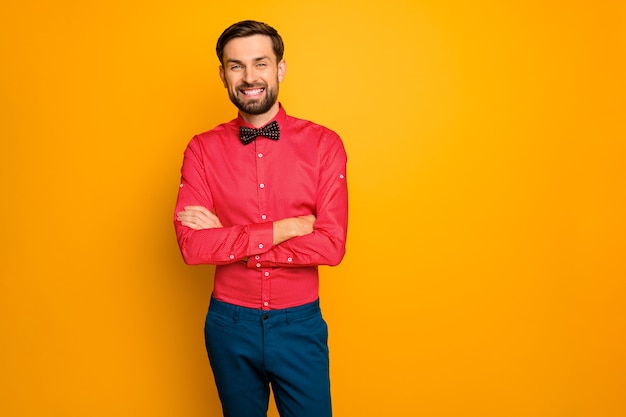 Foto van aantrekkelijke macho zakenman armen gekruist vriendelijke persoon betrouwbare werknemer dragen stijlvol rood shirt met zwarte vlinderdas blauwe broek