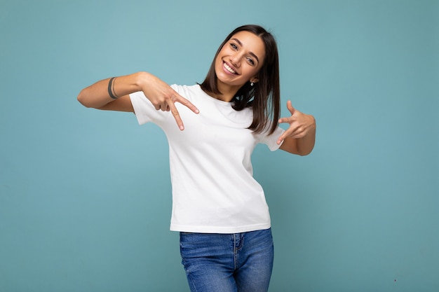 Foto van aantrekkelijke positieve glimlachende jonge vrouw wijzende vingers