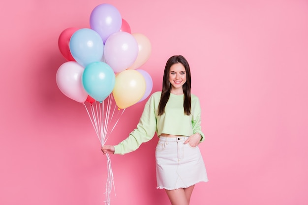 Foto van aantrekkelijke vrolijke dame regelen verrassing verjaardagsfeestje voor beste vriend houden veel luchtballonnen dragen casual groene crop pullover jeans minirok geïsoleerde roze pastel kleur achtergrond