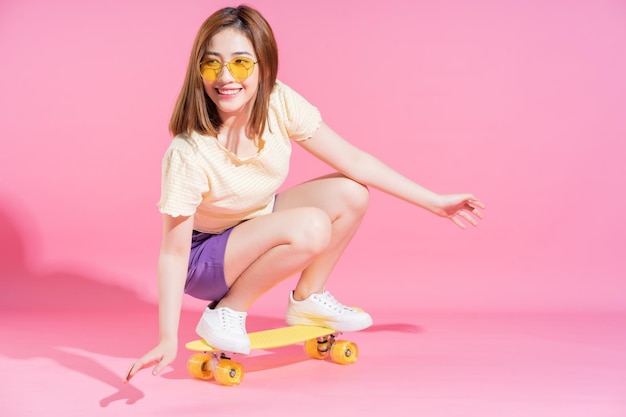 Foto van Aziatisch tienermeisje met skateboard op roze achtergrond