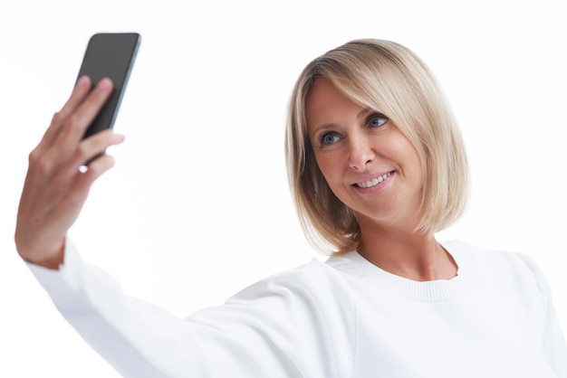 Foto van blonde vrouw over geïsoleerde achtergrond met mobiele telefoon