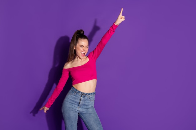 Foto van charmant energiek meisje steek handvinger op en draag spijkerbroek roze ongeklede schouders boven geïsoleerde violette kleurachtergrond