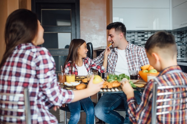 Foto foto van de achterkant. vrolijke man en zijn dochter eten eten tijdens het ontbijt thuis.