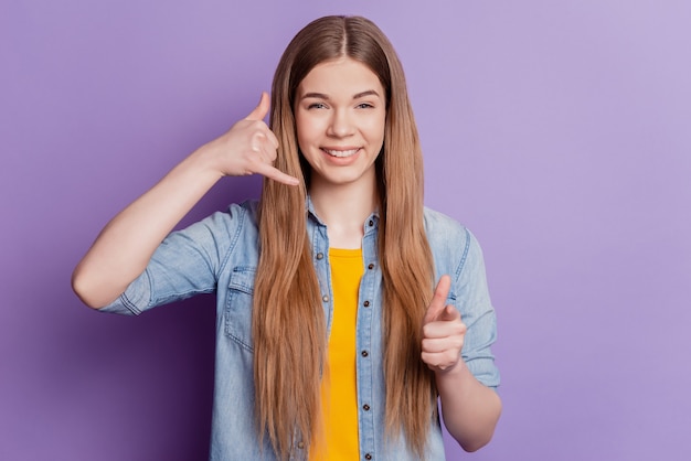 Foto van de directe vinger van het adviseurmeisje, je laat een gebaartelefoon zien op een paarse achtergrond