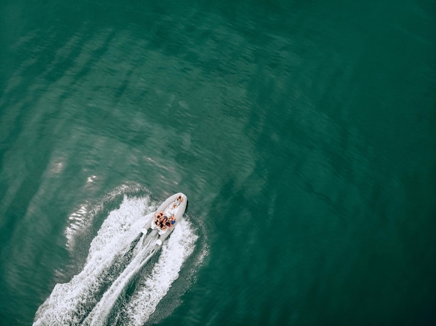 Foto van de drone. Fotosessie op een witte motorboot op de turquoise zee. Een man met een professionele camera maakt foto's van jonge schattige meisjes in zwemkleding. Het concept van een spannende fotoshoot.