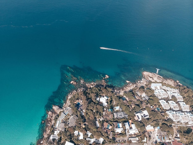 Foto van de helikopter. Kleine buitenlandse stad in de buurt van het grote kata-strand. Boten drijven op het water. De hele stad is bedekt met groene bomen en palmbomen. Veel gebouwen en verschillende locaties.