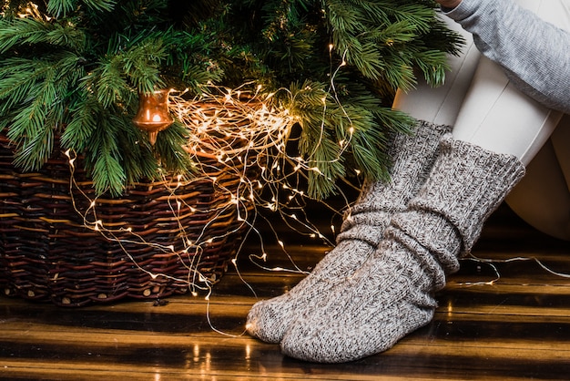 Foto van de onderkant van de kerstboom en de benen in warme sokken