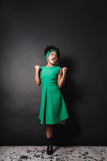 Foto van de volledige lengte van vrolijke afro Amerikaanse dame die groene kleding status draagt