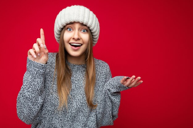 Foto van een aantrekkelijke, positief verraste jonge vrouw die met de vinger omhoog wijst naar copyspace die advertenties presenteert