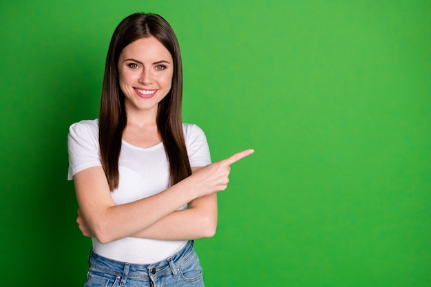 Foto van een aantrekkelijke zelfverzekerde jonge dame draagt een casual outfit met gekruiste armen wijzend op een lege ruimte geïsoleerde groene kleur achtergrond