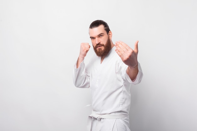 Foto van een bebaarde man in taekwondo-uniform gevecht voorbereiden, kom op