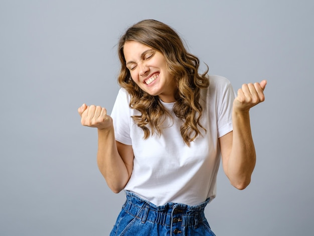 Foto van een charmante vrouw in een wit T-shirt die geïsoleerd danst.