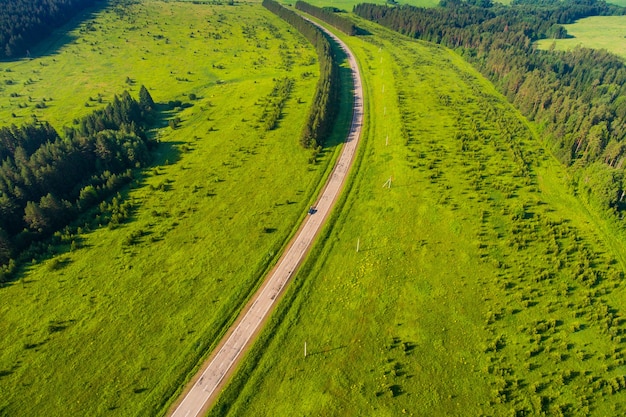 Foto van een drone een weg die in de verte gaat tegen de achtergrond van een groen bos