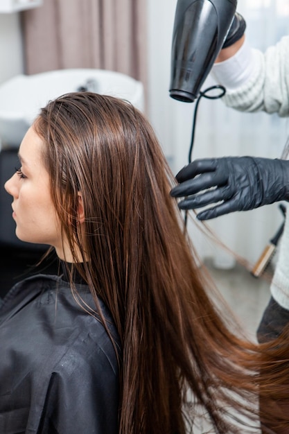 foto van een Europees meisje met lang en mooi bruin haar in de schoonheidssalon glanzend haar