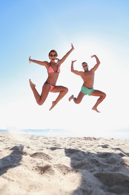 Foto van een gelukkig paar dat op het strand springt.