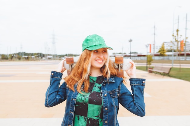 Foto van een jong mooi meisje dat buiten loopt met een skateboard tienergeneratie z