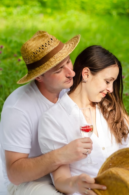 Foto van een jong stel dat in het veld rust en champagne drinkt