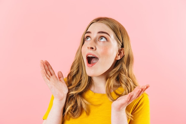 Foto van een jong verrast emotioneel schattig meisje geïsoleerd over roze muur opzij kijkend.