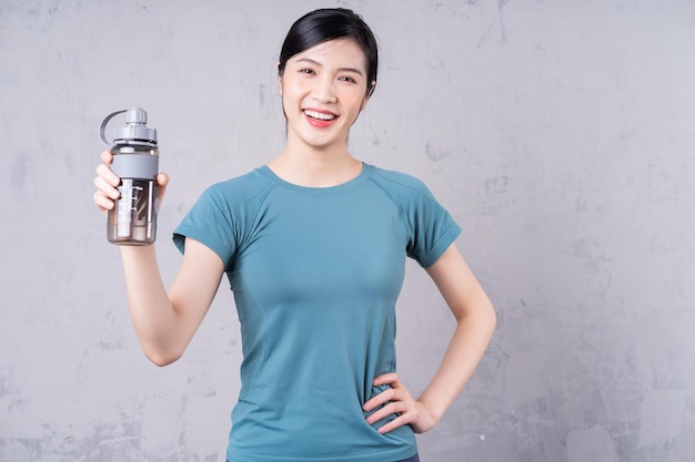 Foto van een jonge Aziatische vrouw die een waterfles vasthoudt