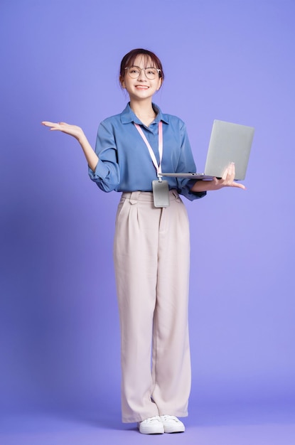 Foto van een jonge Aziatische zakenvrouw die laptop op de achtergrond houdt