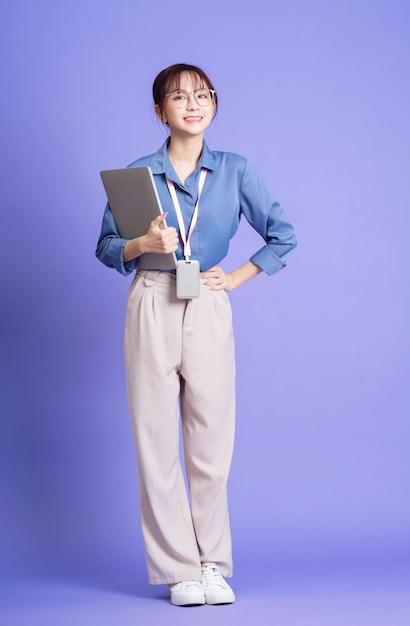 Foto van een jonge Aziatische zakenvrouw die laptop op de achtergrond houdt