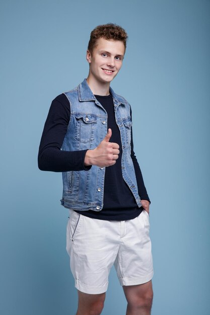 Foto van een jonge man met pizzadozen. Denim vest, witte korte broek, zwarte top met mouwen. Man poseren